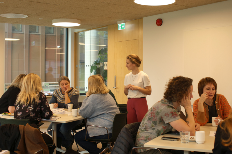 Deltakarne sitter rundt bordene og snakker.