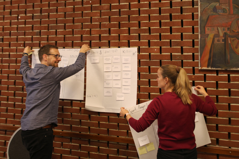 To personer henger opp plakater på veggen.