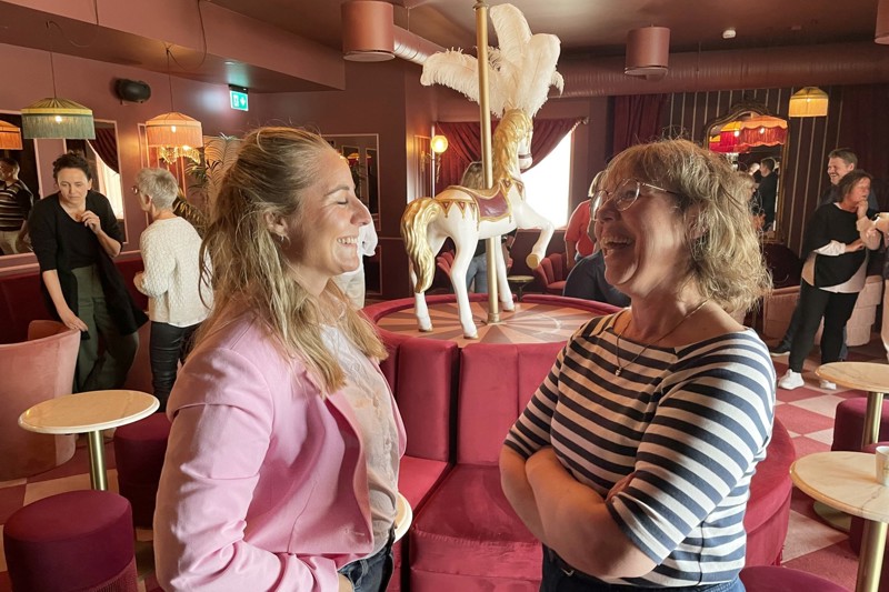 To deltakere snakker med hverandre, mens andre står bak i rommet.