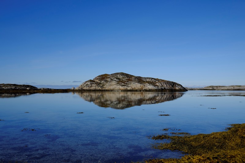 En liten holme i blank sjø