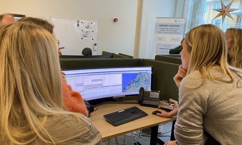 Vi ser personer som kikker på en av skjermene under omvisningen på Værnes responssenter.