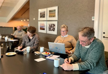 Bildet viser flere av deltakerne på samlingen som sitter ved borden og noterer.