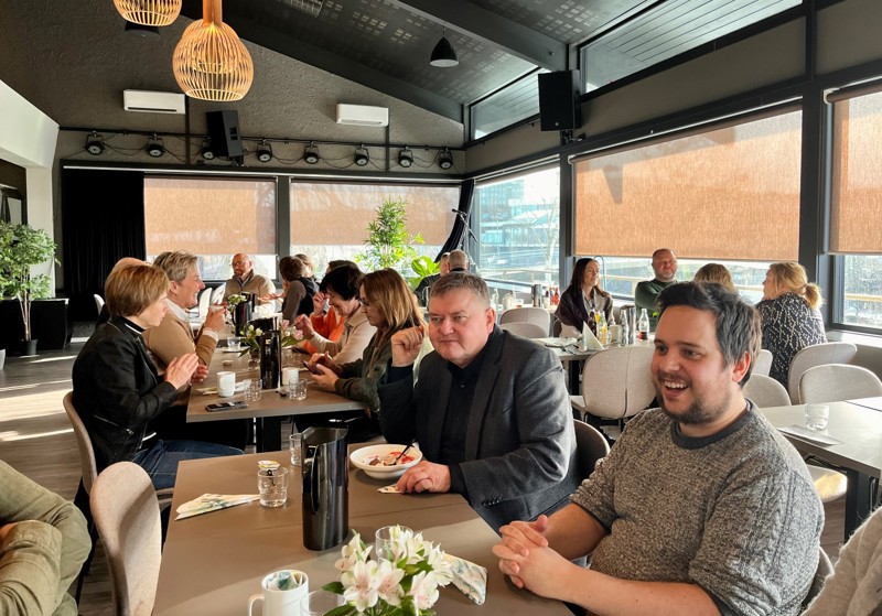 Bildet viser to bord med deltakere som spiser lunsj og hygger seg.