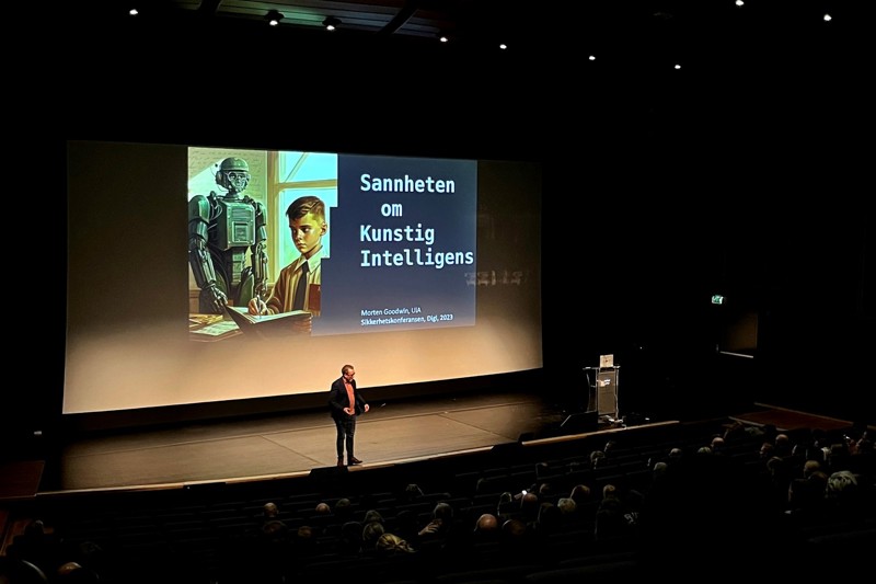 Morten Goodwin, professor ved Universitetet i Agder er ekspert på digitalisering AI holdt to foredrag om tema. Bildet viser Morten Goodwin på scenen og folk som sitter i salen. På den store skjermen bak han står det "sannheten om kunstig intelligens".